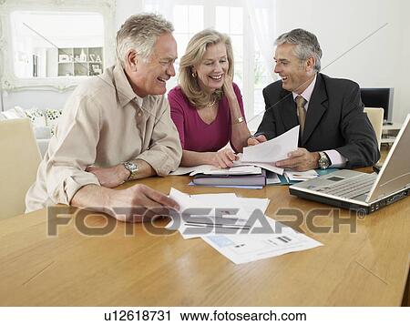 Stock Image - Senior couple sitting at table with financial advisor. Fotosearch