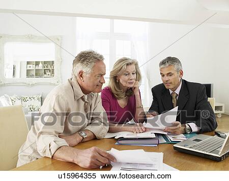 Stock Photography - Senior couple sitting at table with financial advisor. Fotosearch