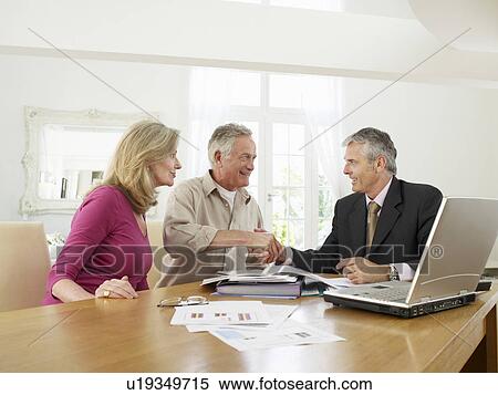 Stock Photography - Senior couple sitting at table with financial advisor. Fotosearch