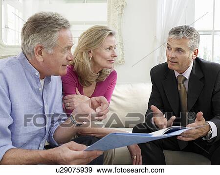 Senior couple sitting on sofa with financial advisor View Large Photo Image Stock Photo - Senior couple sitting on sofa with financial advisor. Fotosearch
