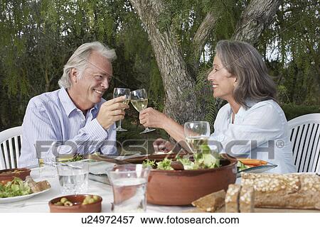 Senior couple toasting at table in garden View Large Photo Image Stock Photo - Senior couple toasting at table in garden. Fotosearch