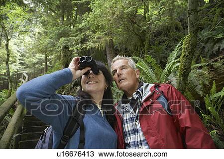 Senior man and middle-aged woman in forest woman looking through binoculars View Large Photo Image Stock Image - Senior man and middle-aged woman in forest woman looking through binoculars. Fotosearch