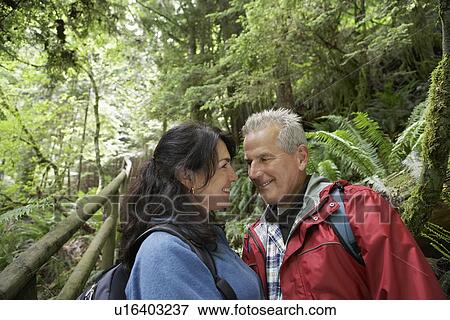 Senior man and middle-aged woman in forest looking in eyes smiling View Large Photo Image Stock Photo - Senior man and middle-aged woman in forest looking in eyes smiling. Fotosearch