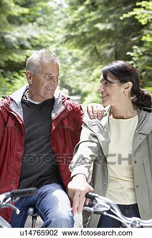 Senior man and middle-aged woman on bikes in forest smiling View Large Photo Image Stock Image - Senior man and middle-aged woman on bikes in forest smiling. Fotosearch