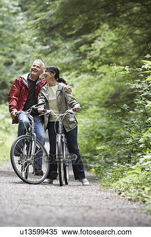 Senior man and middle-aged woman on bicycles in forest laughing View Large Photo Image Stock Photography - Senior man and middle-aged woman on bicycles in forest laughing. Fotosearch