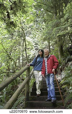 Senior man and middle-aged woman walking on forest trail View Large Photo Image Stock Image - Senior man and middle-aged woman walking on forest trail. Fotosearch