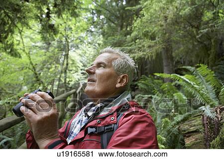 Senior man in forest looking up holding binoculars View Large Photo Image Stock Image - Senior man in forest looking up holding binoculars. Fotosearch