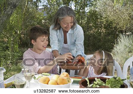 Senior woman serving fruit to children (6-11) in garden View Large Photo Image Stock Photo - Senior woman serving fruit to children (6-11) in garden. Fotosearch