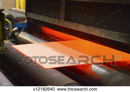 Stock Image - Sheet of orange-coloured material being fed through machine. Fotosearch