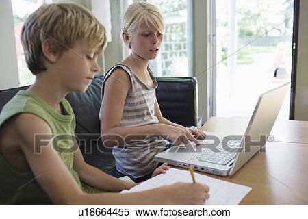 Siblings (6-8) sitting at table doing homework with laptop View Large Photo Image Stock Photography - Siblings (6-8) sitting at table doing homework with laptop. Fotosearch