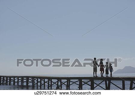 Picture - Silhouettes of parents and children (6-11) on jetty. Fotosearch