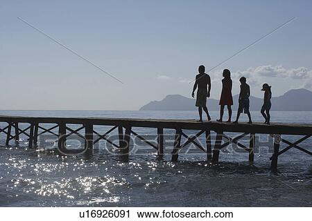 Silhouettes of parents and children (6-11) walking on jetty View Large Photo Image Stock Image - Silhouettes of parents and children (6-11) walking on jetty. Fotosearch