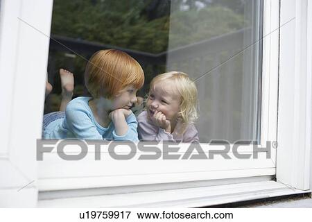 Stock Photo - Sisters (3-6) indors in front of window. Fotosearch