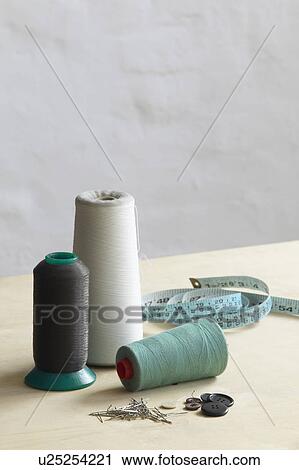 Stock Image - Spools of thead pins and measuring tape on table. Fotosearch