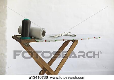Spools of thread and scissors on ironing board indoors View Large Photo Image Stock Photograph - Spools of thread and scissors on ironing board indoors. Fotosearch