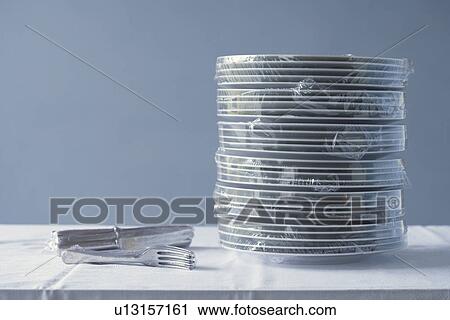 Stack of plates and cutlery wrapped in plastic on table View Large Photo Image Stock Image - Stack of plates and cutlery wrapped in plastic on table. Fotosearch