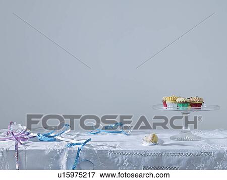 Stock Photo - Streamers and cup cakes on table. Fotosearch