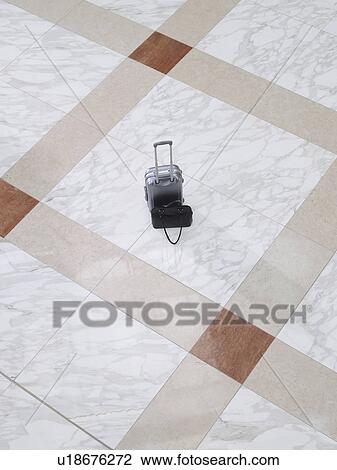 Stock Image - Suitcase and handbag on tiled floor elevated view. Fotosearch