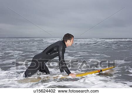 Surfer holding surfboard in water side view View Large Photo Image Stock Image - Surfer holding surfboard in water side view. Fotosearch