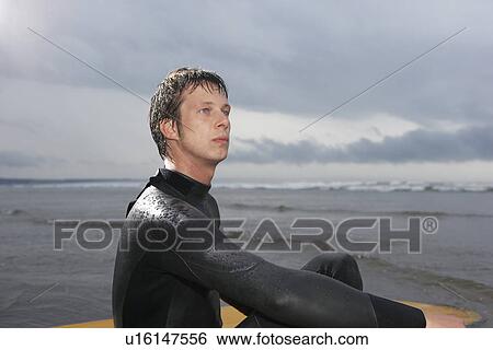 Surfer sitting surfboard in water side view View Large Photo Image Stock Photograph - Surfer sitting surfboard in water side view. Fotosearch