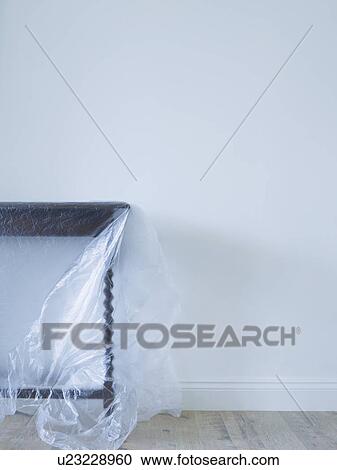 Stock Image - Table covered with plastic in empty room. Fotosearch