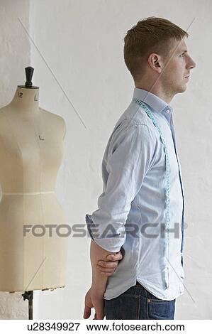 Tailor standing next to mannequin side view View Large Photo Image Stock Photo - Tailor standing next to mannequin side view. Fotosearch