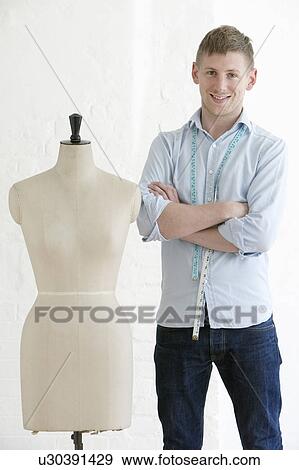 Tailor standing next to mannequin portrait View Large Photo Image Stock Photo - Tailor standing next to mannequin portrait. Fotosearch