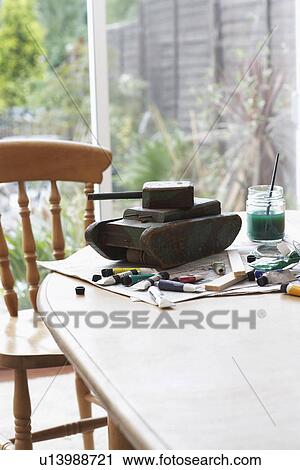 Stock Image - Tank model and painting equipment on table close-up. Fotosearch