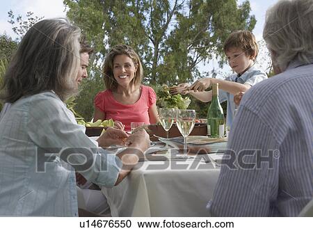 Three-generation family including boy (5-6) dining in garden View Large Photo Image Stock Image - Three-generation family including boy (5-6) dining in garden. Fotosearch