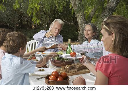 Three-generation family with children (6-11) dining in garden View Large Photo Image Stock Image - Three-generation family with children (6-11) dining in garden. Fotosearch