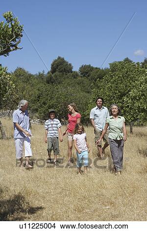 Picture - Three-generation family with two children (6-11) walking in field. Fotosearch