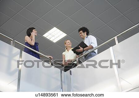 Three people standing at railing of indoor balcony View Large Photo Image Stock Image - Three people standing at railing of indoor balcony. Fotosearch
