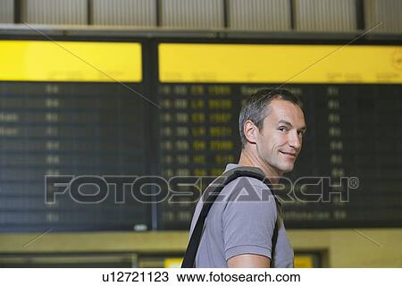 Traveller in front of flight status board in airport View Large Photo Image Stock Image - Traveller in front of flight status board in airport. Fotosearch