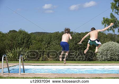 Two boys (6-11) jumping into pool back view View Large Photo Image Picture - Two boys (6-11) jumping into pool back view. Fotosearch