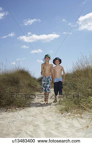 Two boys (6-11) walking in sand dunes with fishing net View Large Photo Image Stock Image - Two boys (6-11) walking in sand dunes with fishing net. Fotosearch