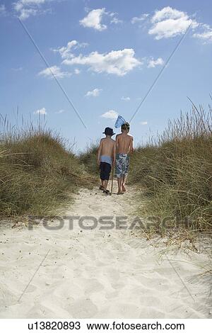 Two boys (6-11) walking in sand dunes with fishing net back view View Large Photo Image Stock Image - Two boys (6-11) walking in sand dunes with fishing net back view. Fotosearch