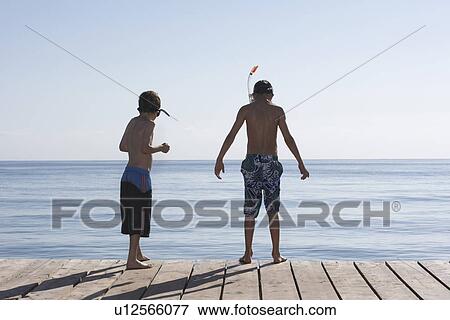 Two boys (7-11) on jetty wearing snorkelling masks back view View Large Photo Image Stock Photo - Two boys (7-11) on jetty wearing snorkelling masks back view. Fotosearch