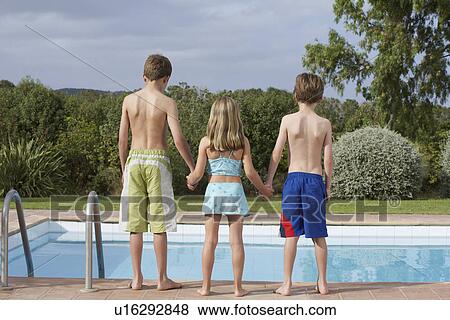 Two boys and girl (6-11) standing on edge of pool back view View Large Photo Image Stock Photo - Two boys and girl (6-11) standing on edge of pool back view. Fotosearch