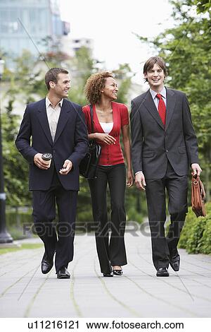 Two business men and woman walking through park View Large Photo Image Stock Image - Two business men and woman walking through park. Fotosearch
