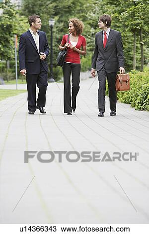 Two business men and woman walking through park View Large Photo Image Stock Image - Two business men and woman walking through park. Fotosearch