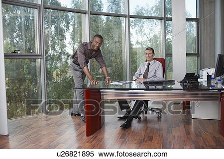 Stock Photography - Two business men at desk in office portrait. Fotosearch