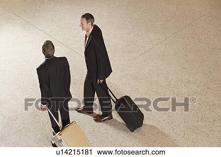 Two business men pulling suitcases in lobby View Large Photo Image Stock Image - Two business men pulling suitcases in lobby. Fotosearch