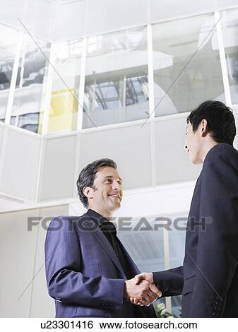 Two business men shaking hands low angle view View Large Photo Image Stock Photograph - Two business men shaking hands low angle view. Fotosearch