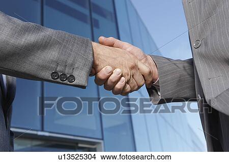 Two business men shaking hands outside office close-up View Large Photo Image Picture - Two business men shaking hands outside office close-up. Fotosearch