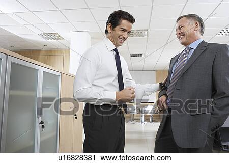 Stock Image - Two business men talking in office. Fotosearch