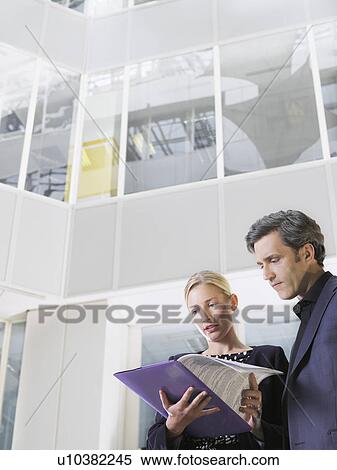 Stock Photography - Two business people looking at paper folder low angle view. Fotosearch