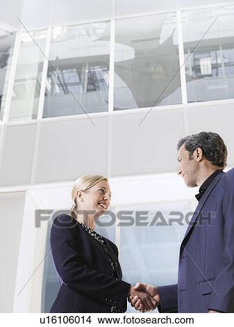 Two business people shaking hands low angle view side view View Large Photo Image Picture - Two business people shaking hands low angle view side view. Fotosearch