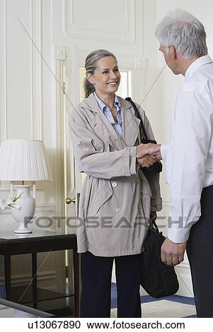 Two business people shaking hands indoors View Large Photo Image Stock Image - Two business people shaking hands indoors. Fotosearch