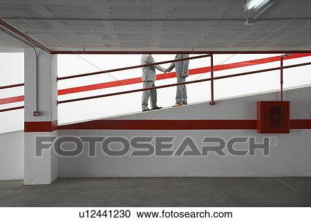Two businessmen shaking hands on ramp in parking garage View Large Photo Image Stock Image - Two businessmen shaking hands on ramp in parking garage. Fotosearch