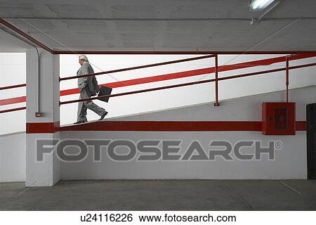 Stock Photograph - Two businessmen walking down ramp in parking garage. Fotosearch